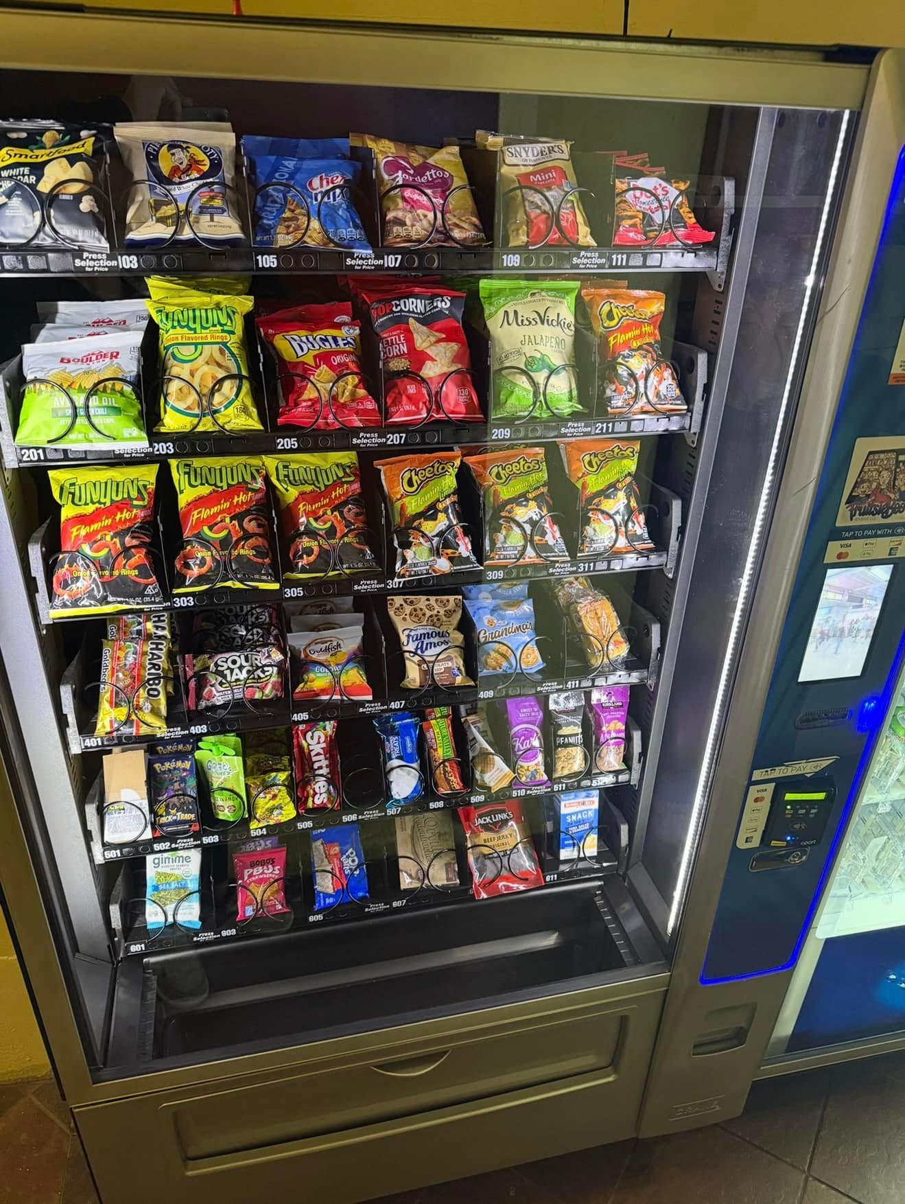 A snack vending machine stocked with various colorful bags of chips and snacks.