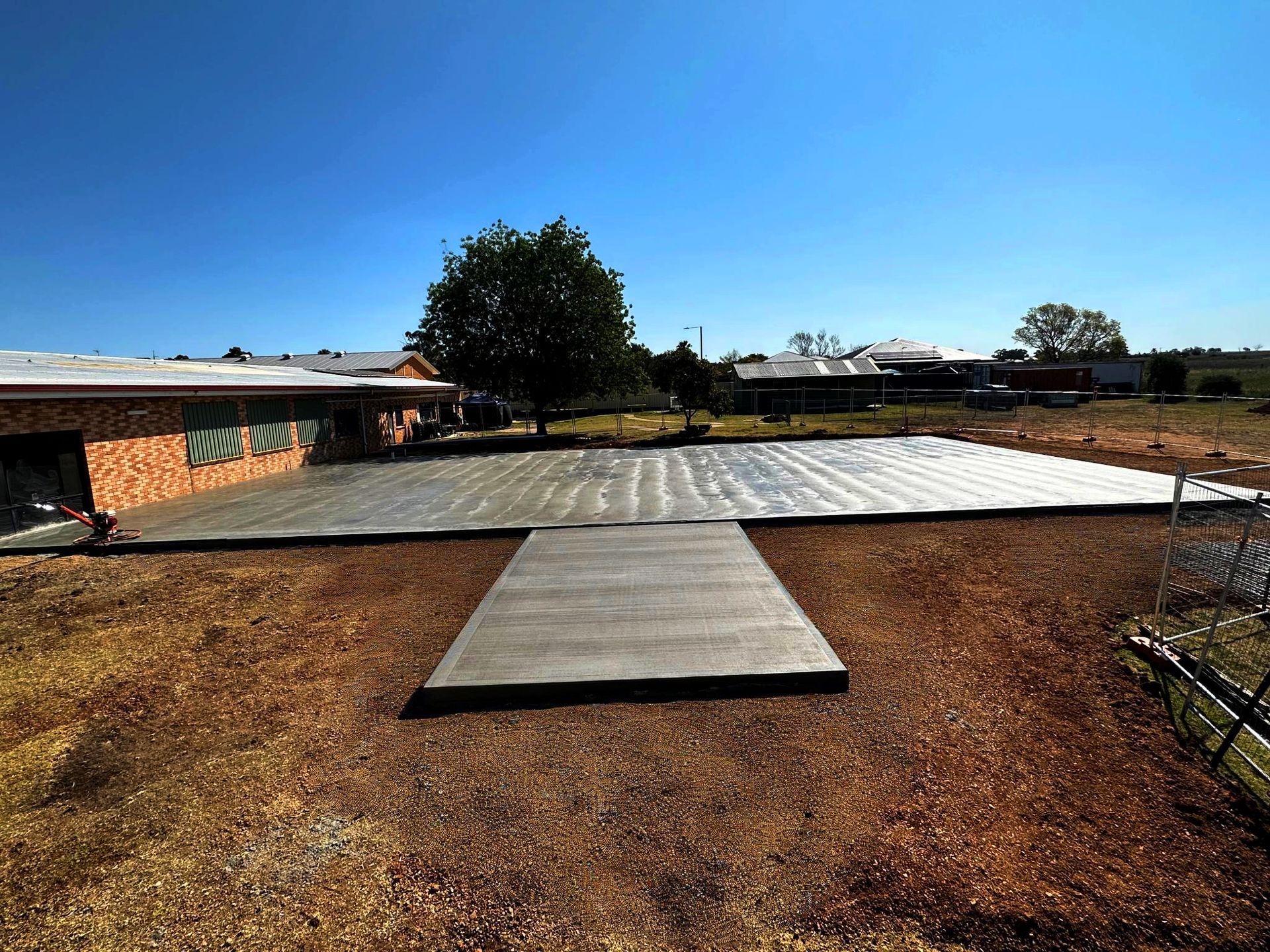 A Red Dump Truck Is Dumping Dirt Into a Field — Spencer's Landscape Construction & Concreting Pty Ltd in Mudgee, NSW