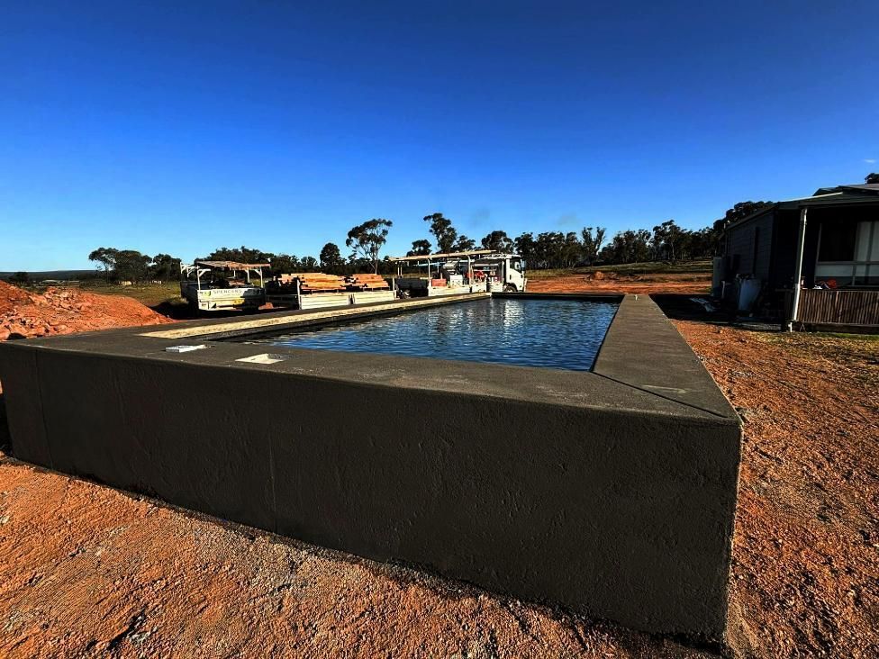 A Large Swimming Pool Sitting in The Middle of A Field — Spencer's Landscape Construction & Concreting Pty Ltd in Dubbo, NSW
