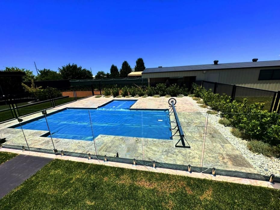 A Swimming Pool Is Surrounded by A Fence and A House — Spencer's Landscape Construction & Concreting Pty Ltd in Dubbo, NSW