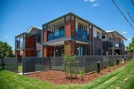 A Large Apartment Building with A Fence Around It — Spencer's Landscape Construction & Concreting Pty Ltd in Dubbo, NSW
