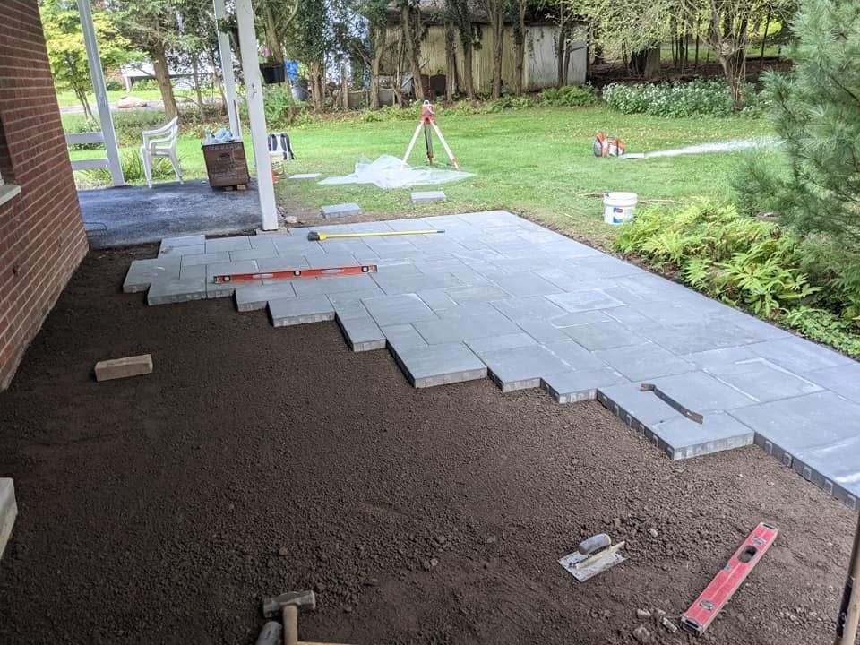 Person laying interlocking pavers in a garden bed.