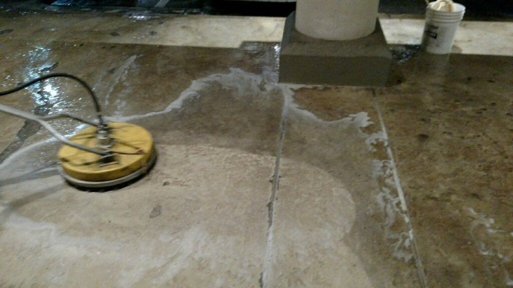 Yellow floor scrubber cleaning a wet concrete floor with a hose attached