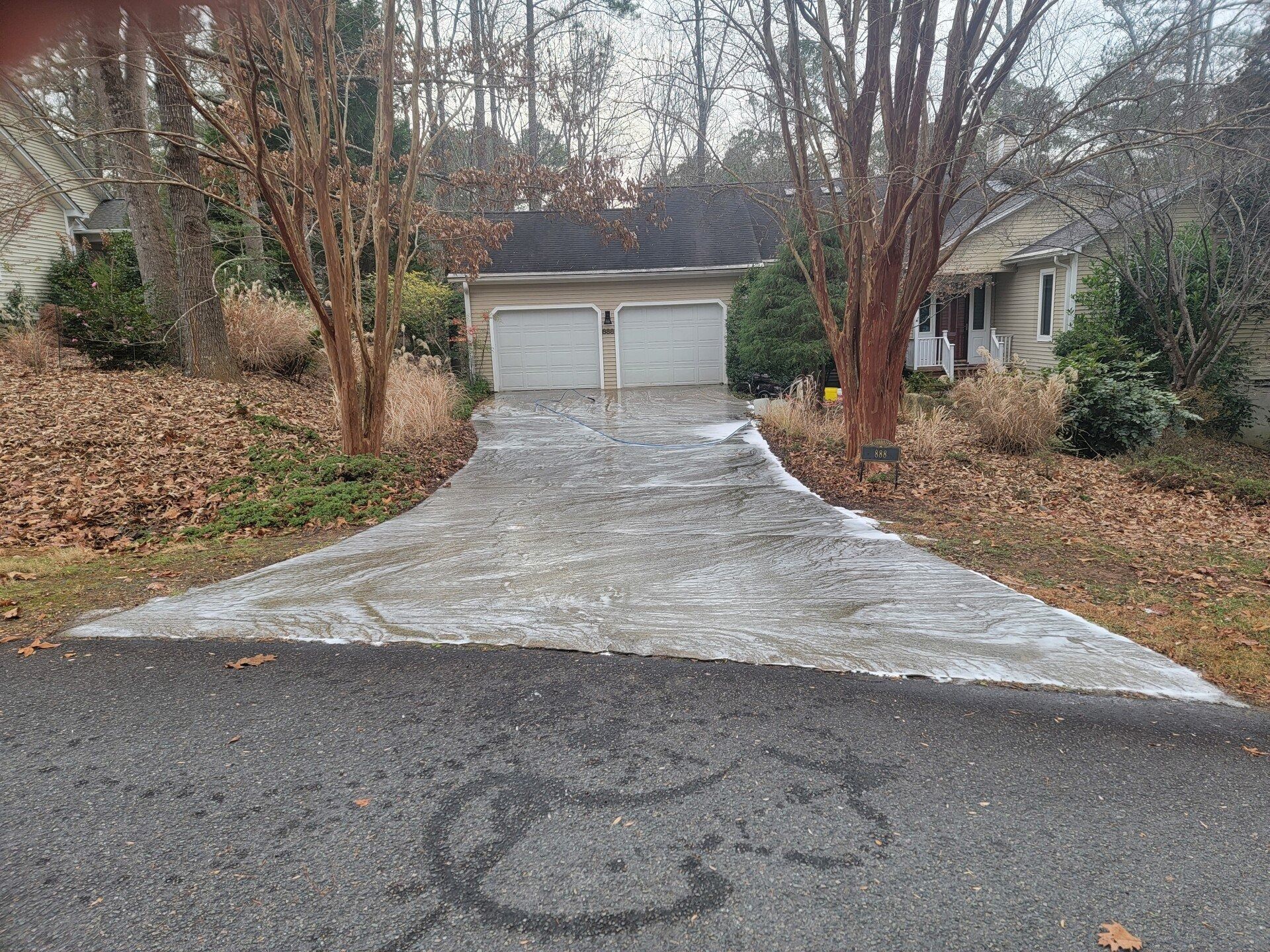 Snow-dusted driveway leading to a two-car garage in a wooded residential area
