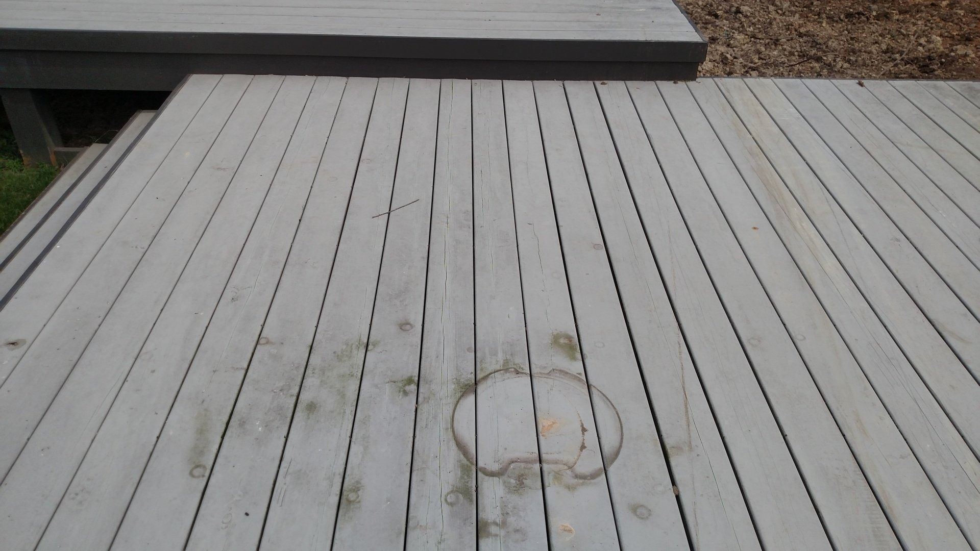 Weathered white wooden deck with a circular stain near the center.