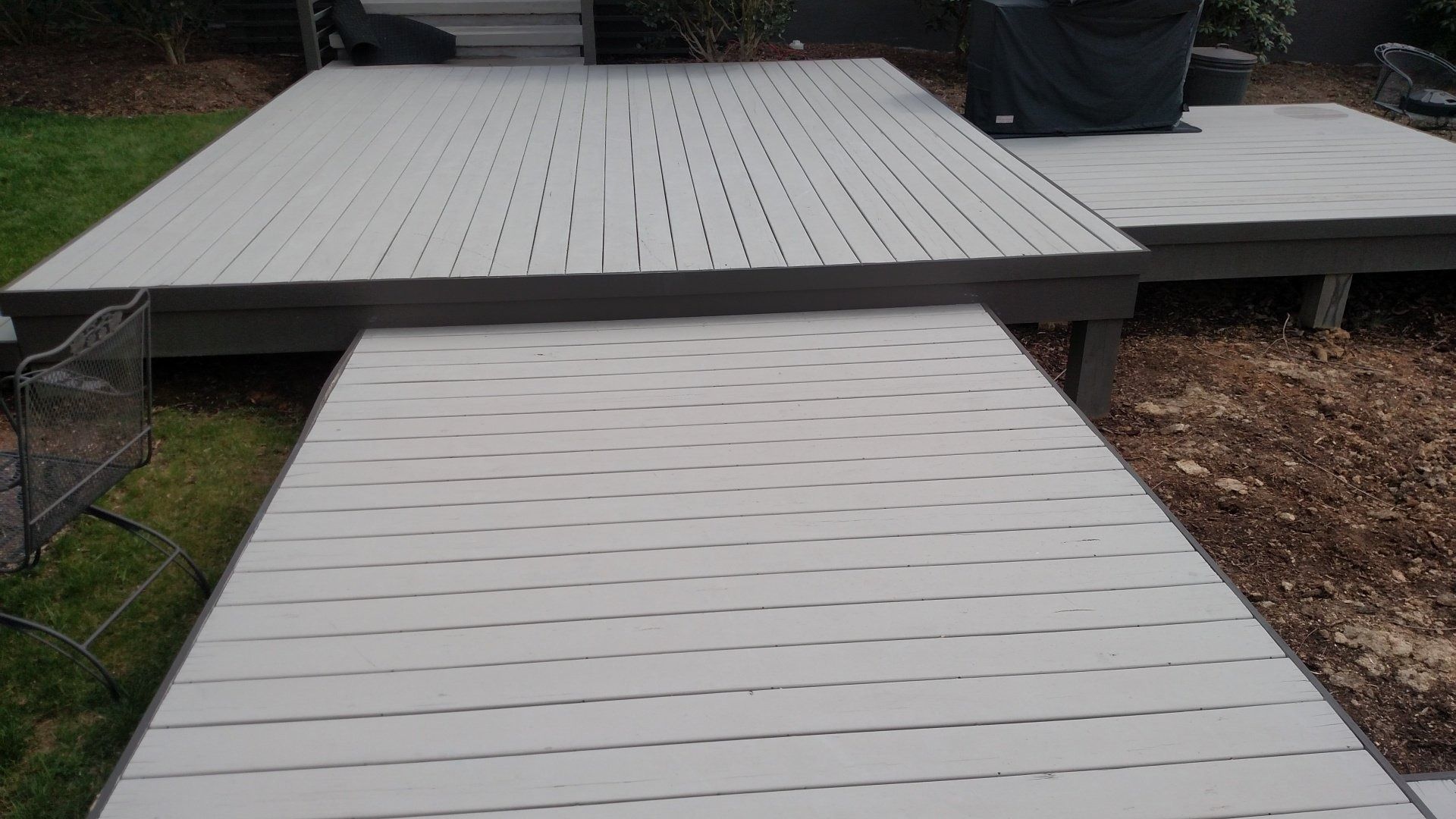 White wooden ramp leading to a raised deck with a dark trim outdoors