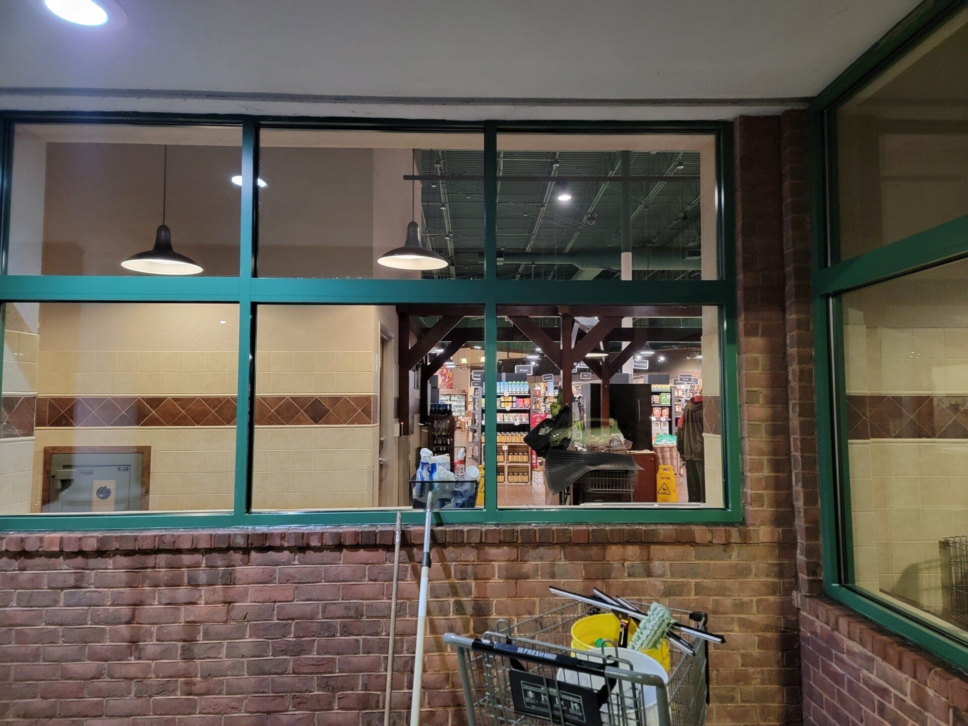Empty brick-walled courtyard with teal-framed windows and a hand truck in the foreground