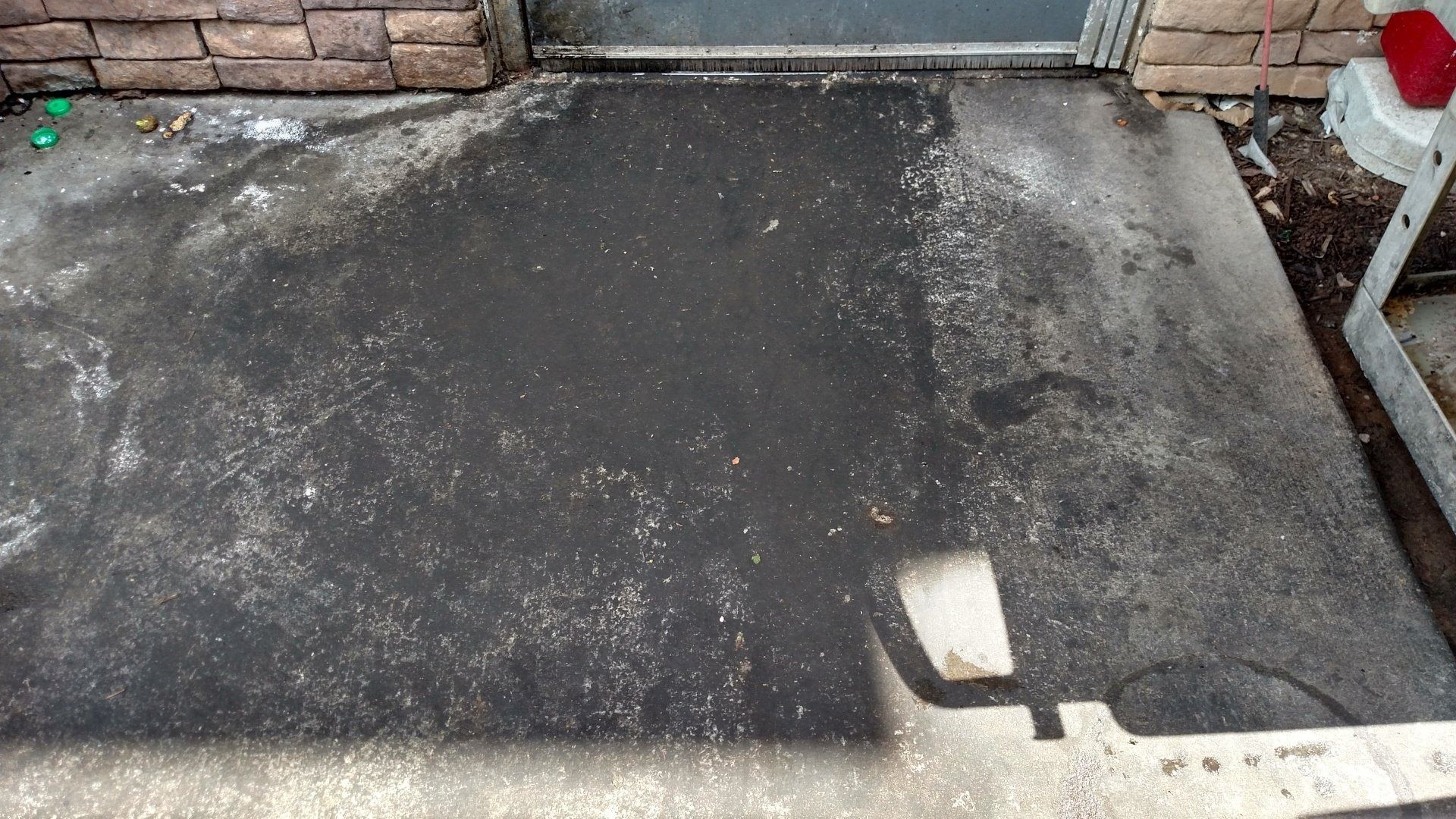 Dark concrete patio or driveway with a stone wall at the top and a small white table on the right.