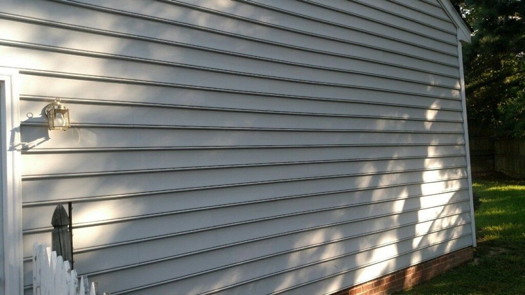 White vinyl house siding with outdoor utility meters and sunlight shadows