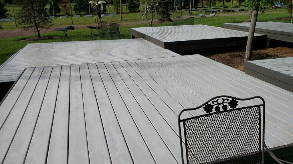 Outdoor wooden deck with a decorative chair in the foreground and a park with trees beyond.