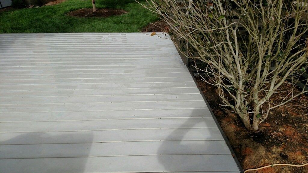 White wooden deck or walkway beside a shrub and mulch in a yard