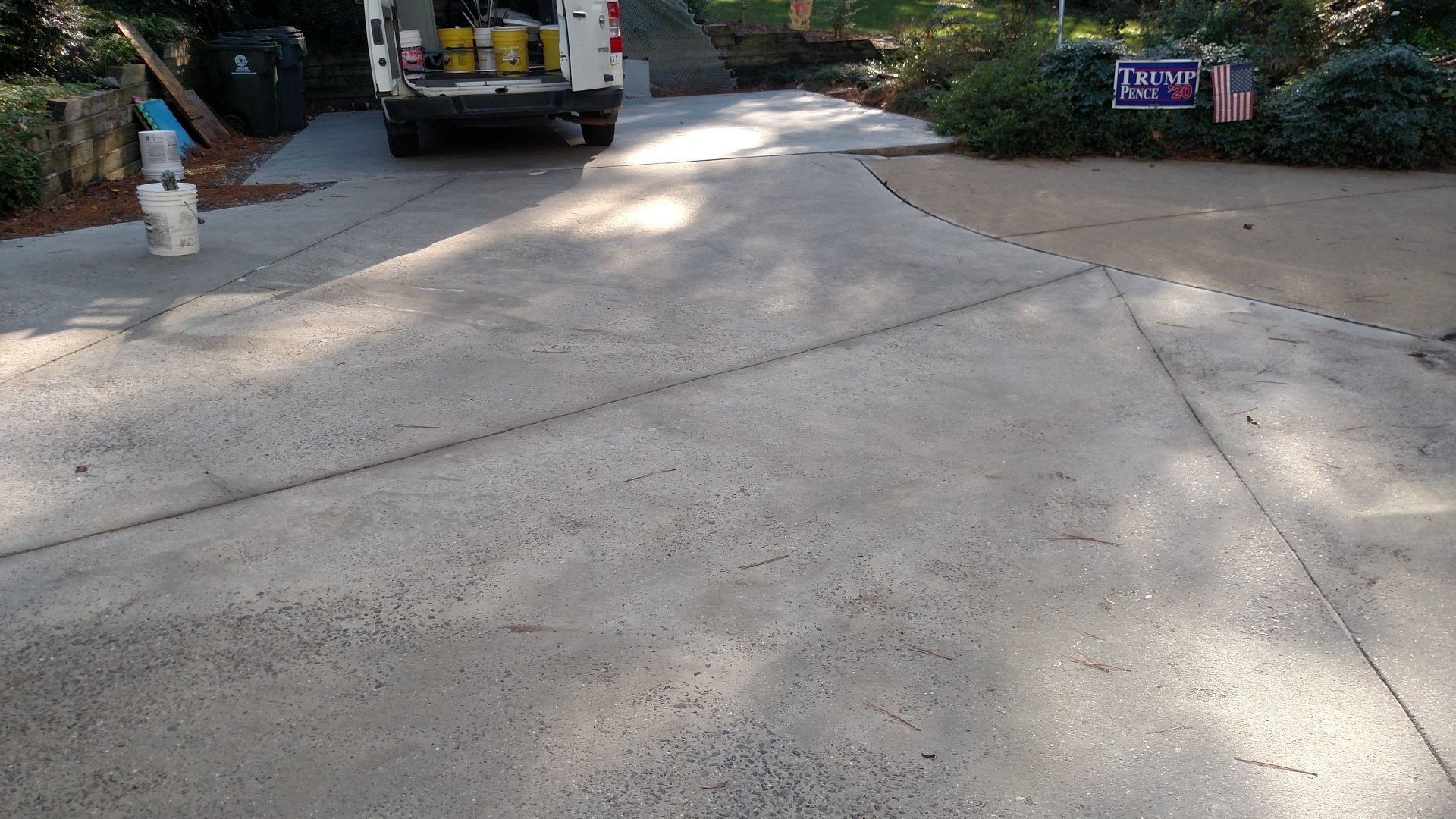 Driveway leading to a parked truck, with a person standing at the left and trees along the sides.