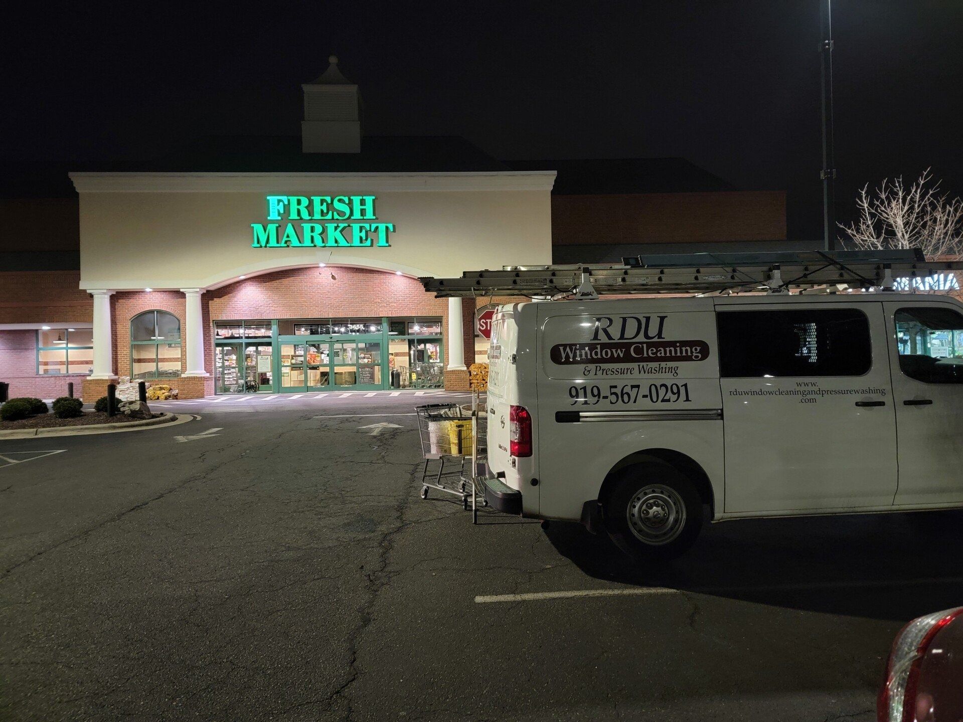 Nighttime view of Fresh Market storefront with a white van parked in front.
