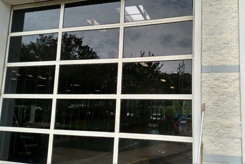 Glass storefront window with white metal framing beside a beige stone wall
