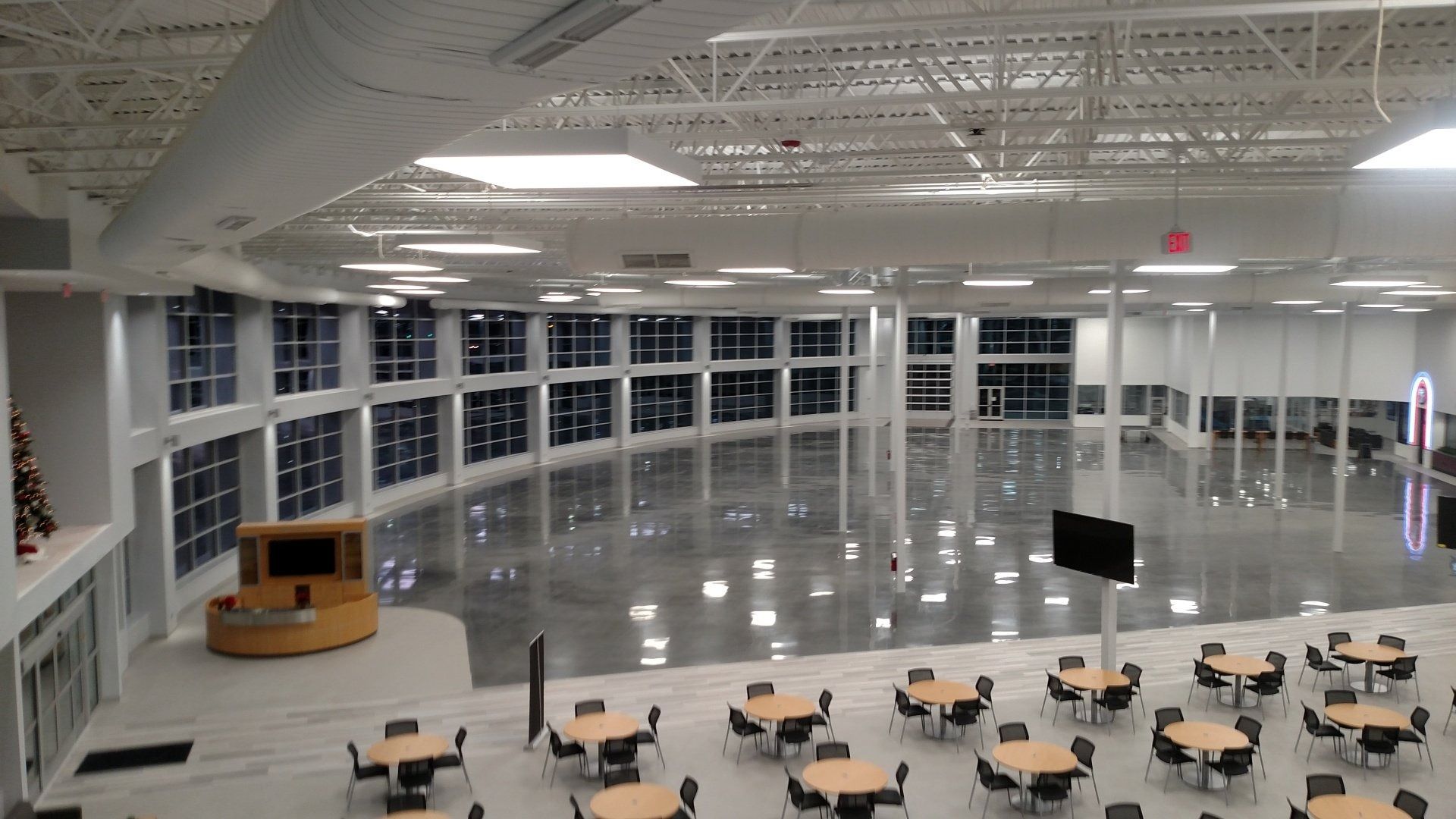 Spacious modern lobby with polished floor, rows of tables and chairs, and large windows along the wall