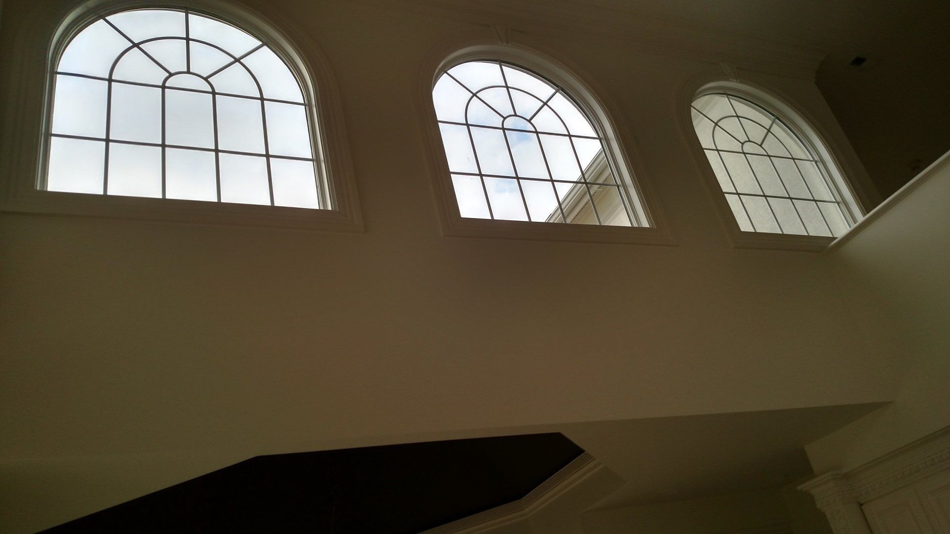 Arched windows with white frames letting light into a dim interior stairwell