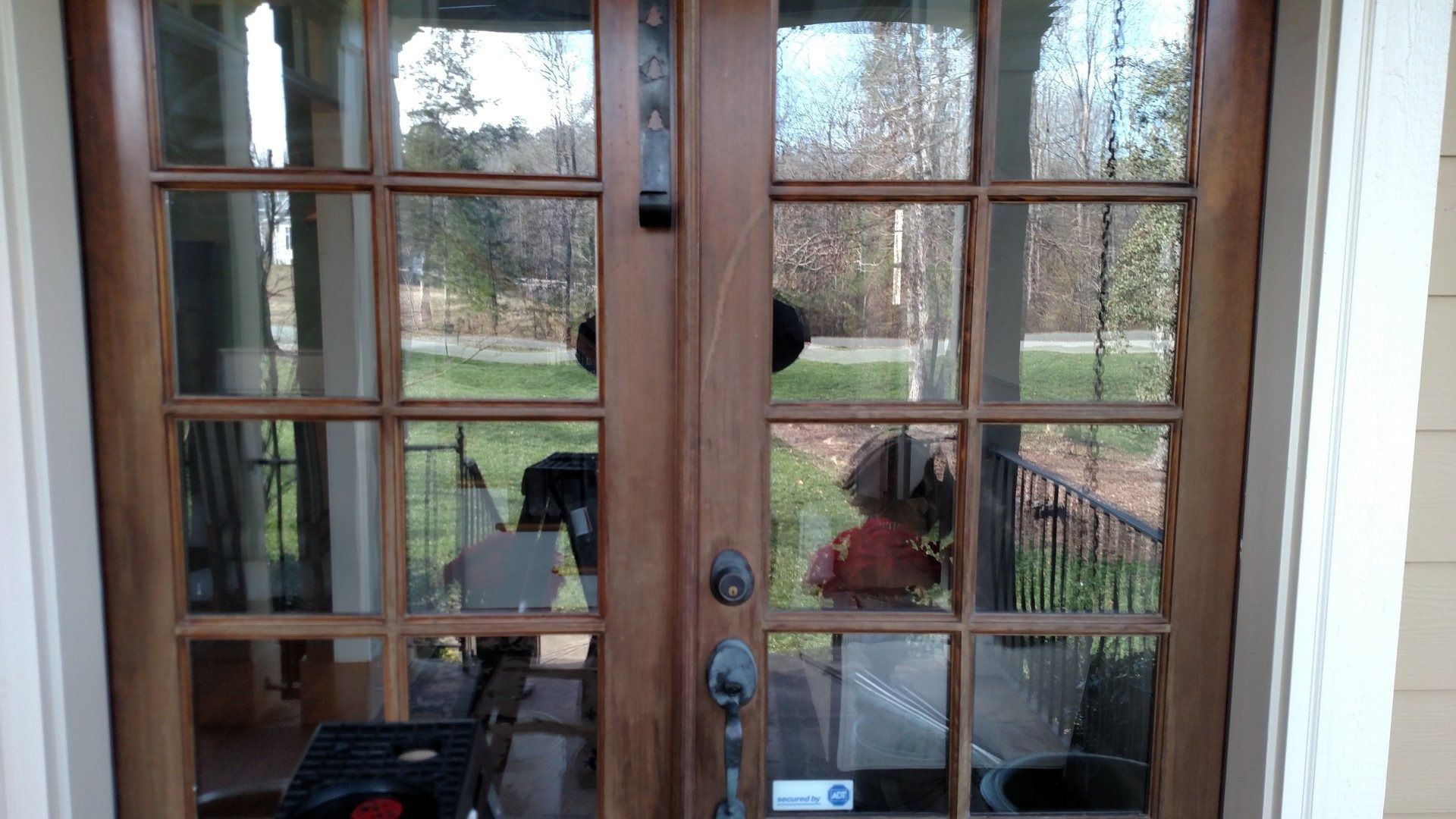 Wooden French doors with glass panes opening to a patio with outdoor furniture and trees beyond