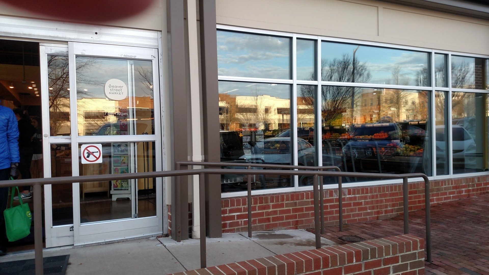 Storefront entrance with glass doors and large windows, brick base, and a person partly visible inside