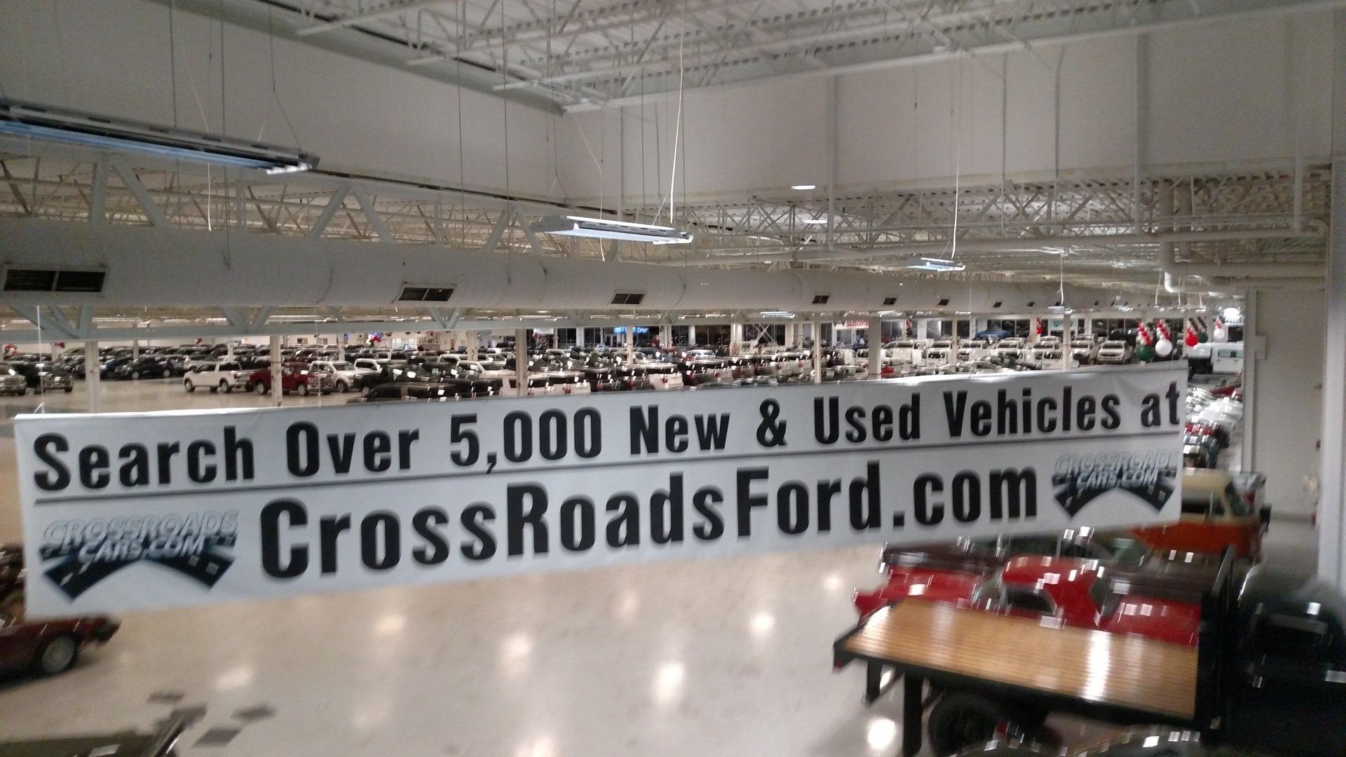 Indoor car showroom with a large CrossRoadsFord.com banner and several vehicles on display.