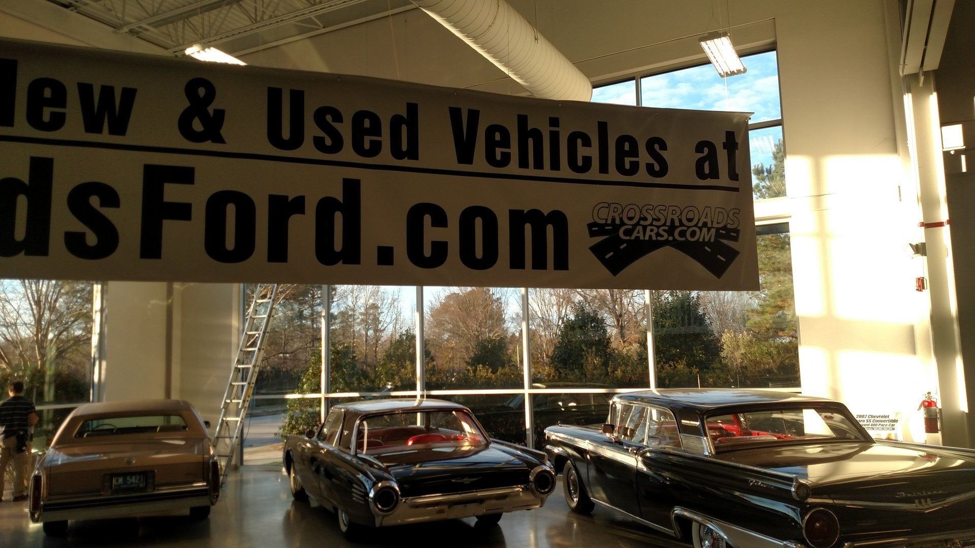 Used car dealership with classic cars under a banner reading “New & Used Vehicles” and “...Ford.com”