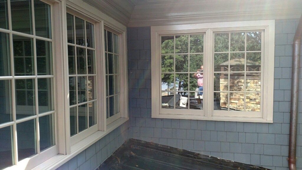 Blue shingled porch with white-framed windows and a view of the backyard through the glass.