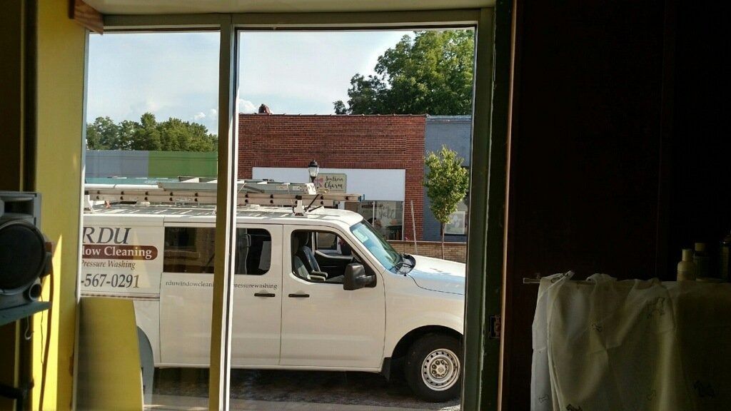 White utility van parked outside a glass storefront, viewed through an open doorway.