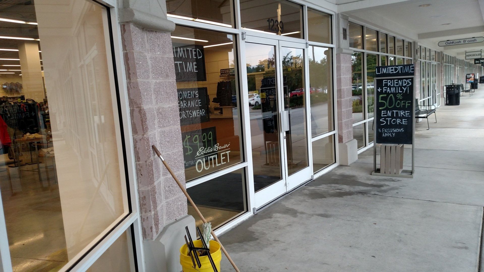 Storefront with glass doors and chalkboard signs along a covered outdoor walkway.