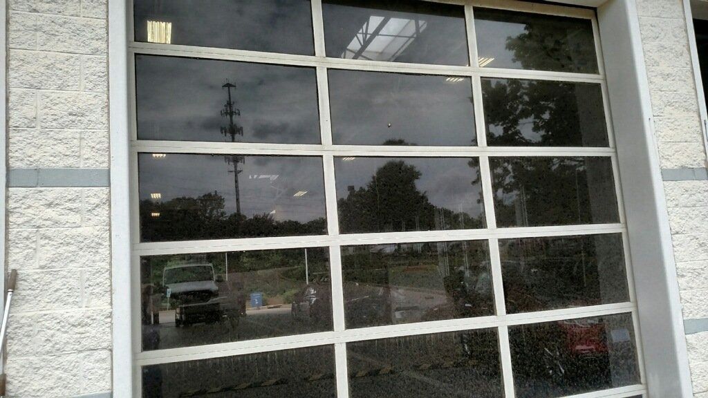 Large window with white grid panes reflecting trees and parked cars outside.