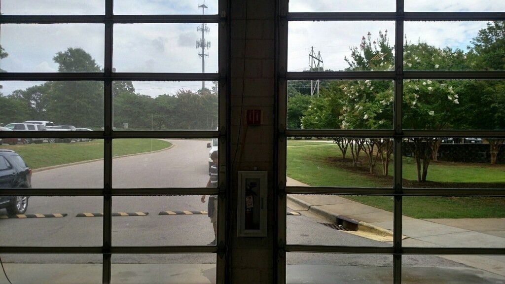 View through glass doors to a rainy parking lot, trees, and a road outside
