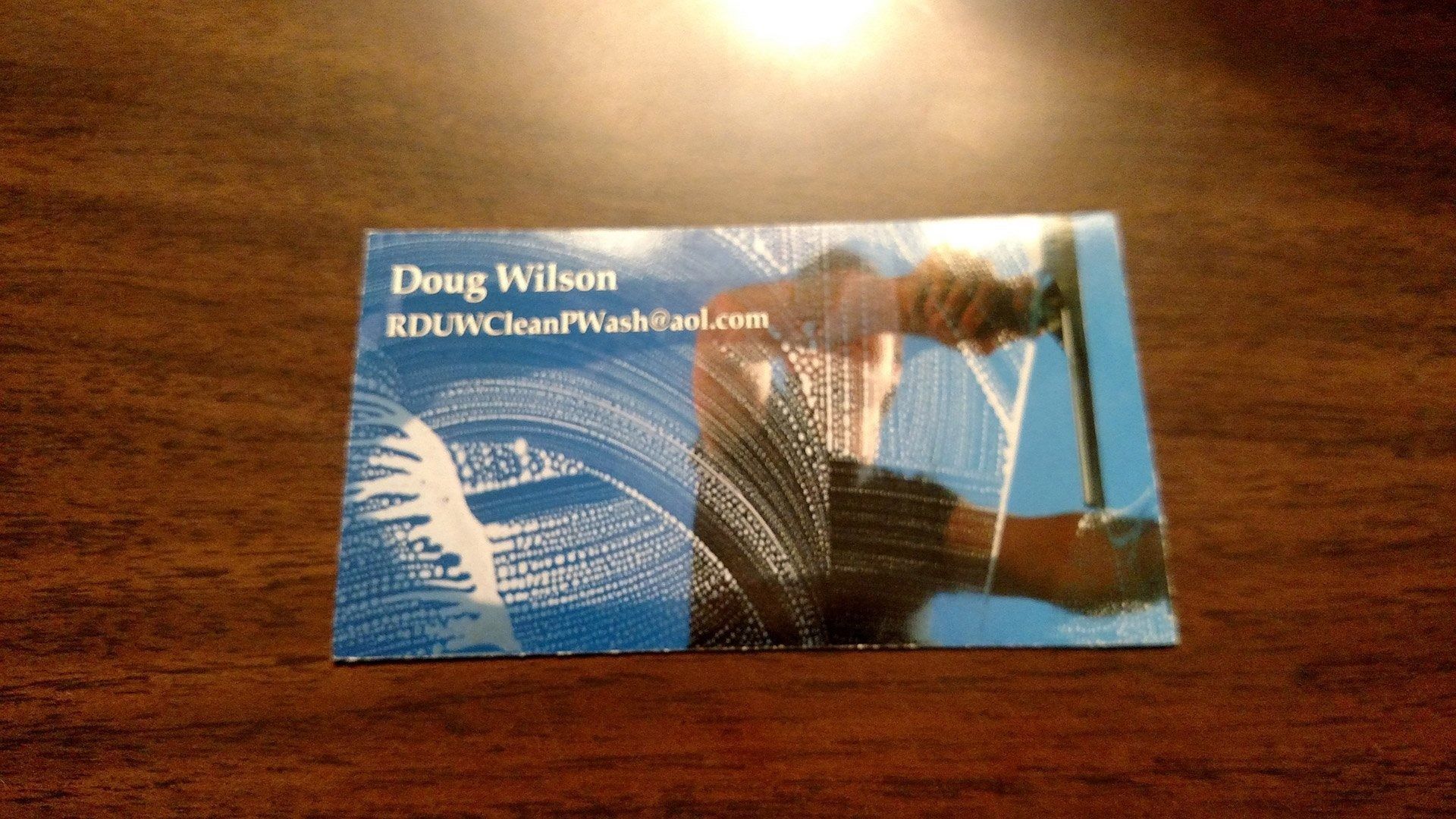 Blue business card on a wooden table with white text and a cityscape design