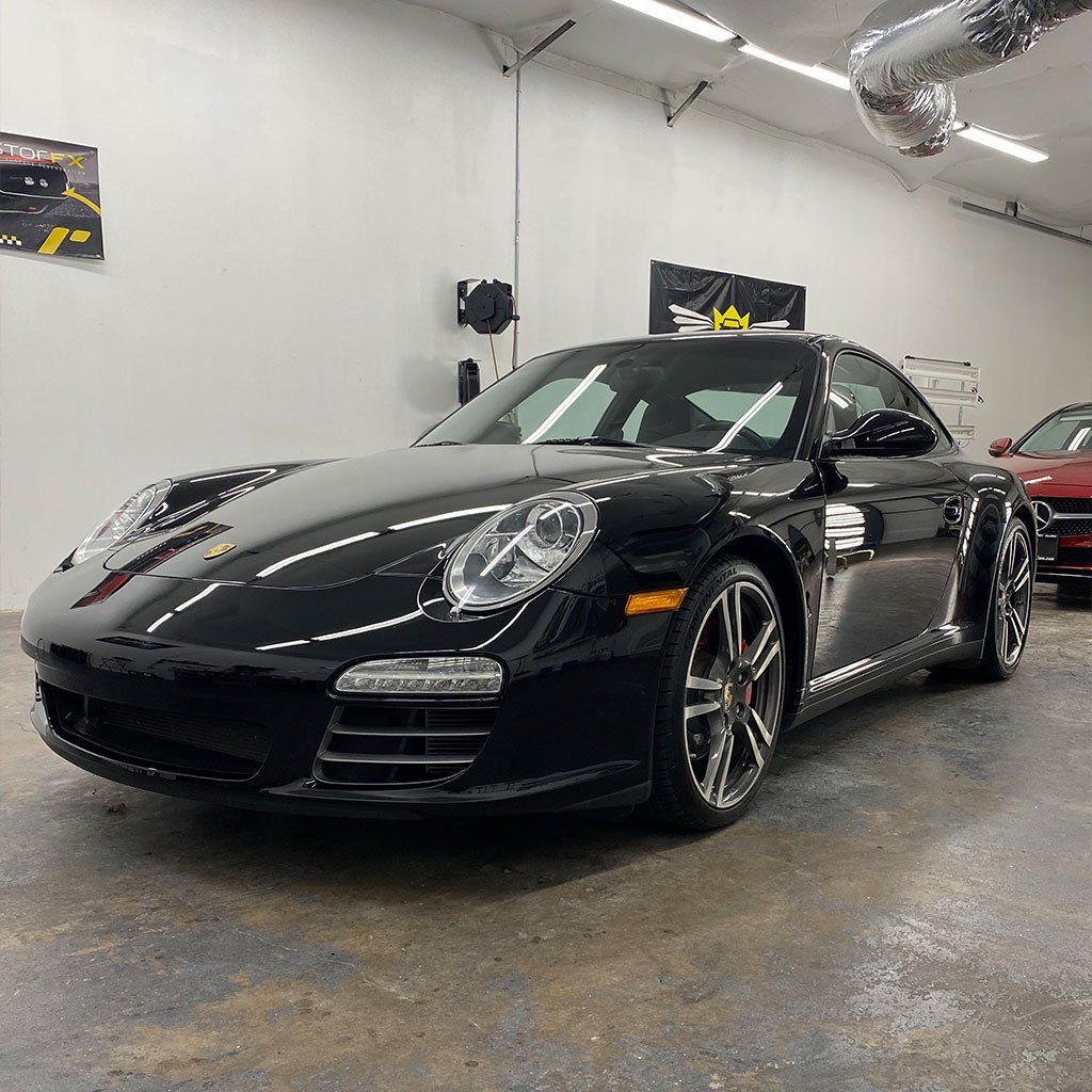 Black Porsche sports car parked in a garage.