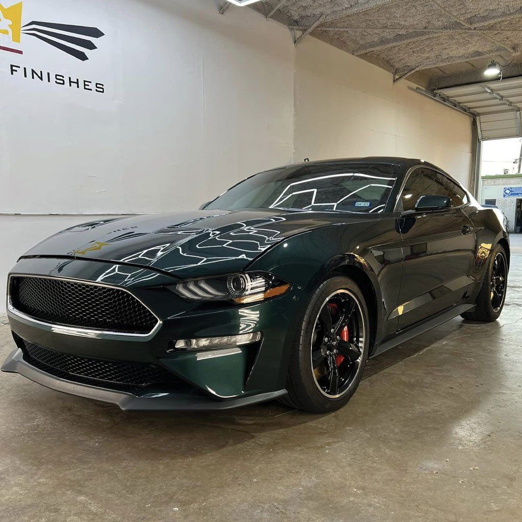 Green Ford Mustang sports car parked inside a garage.