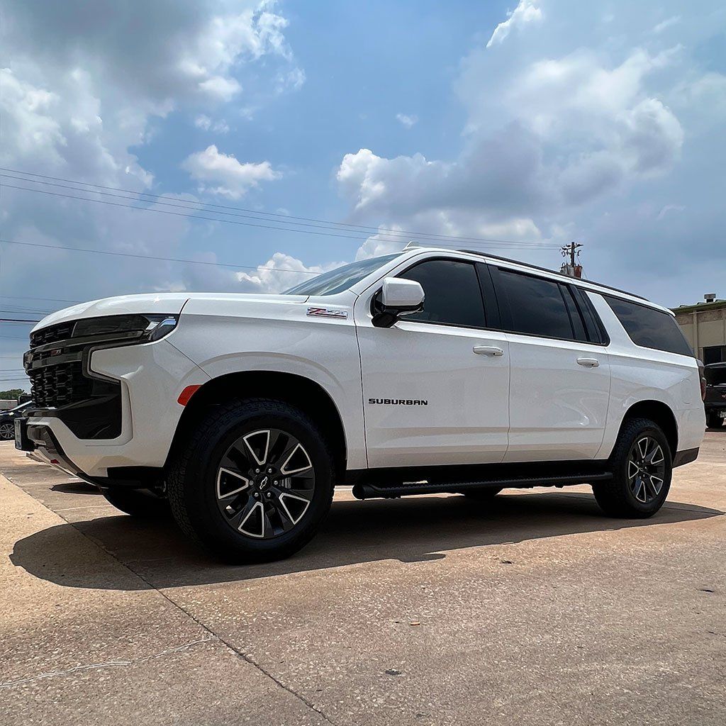 White Chevy Suburban SUV parked outside on a sunny day.