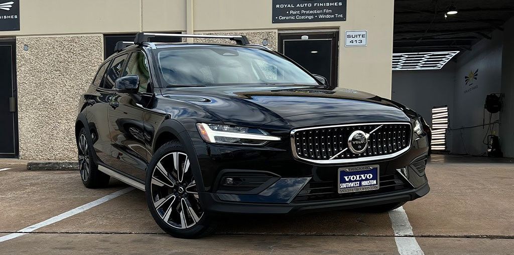 Black Volvo SUV parked in front of a building with a white parking line.