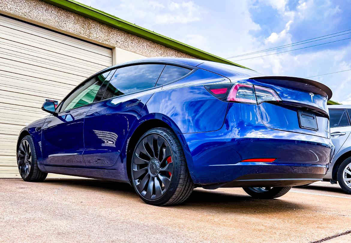 Blue Tesla parked in front of a garage, low angle shot.