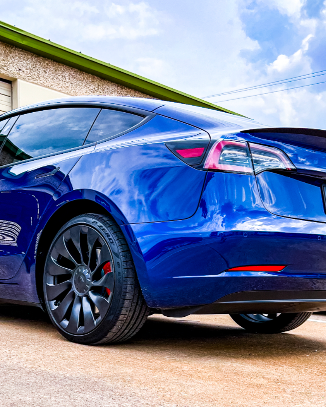 Blue car with tinted windows in a garage with a sign that says