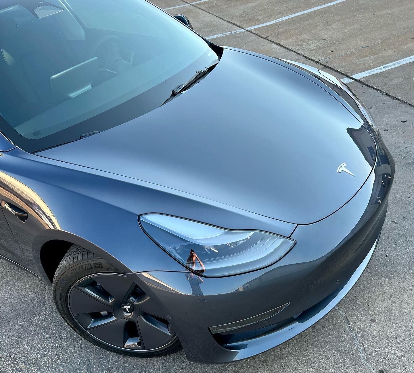 Gray Tesla Model 3 car parked on a paved surface.