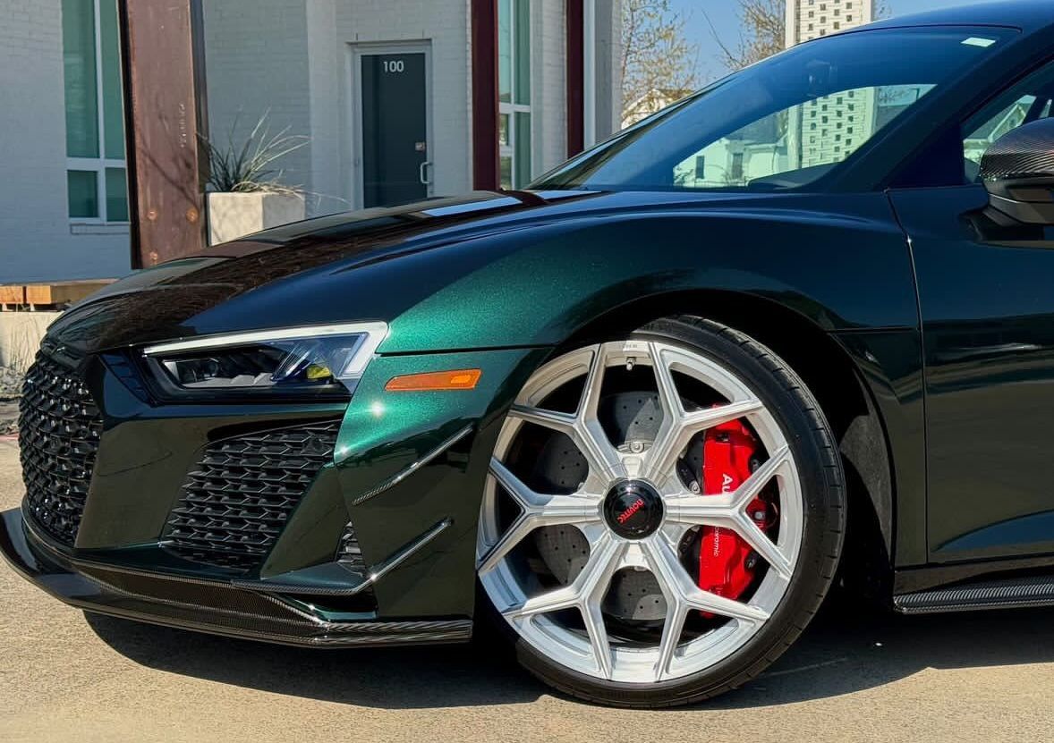 Green Audi R8 sports car with silver wheels and red brake calipers, parked outdoors.