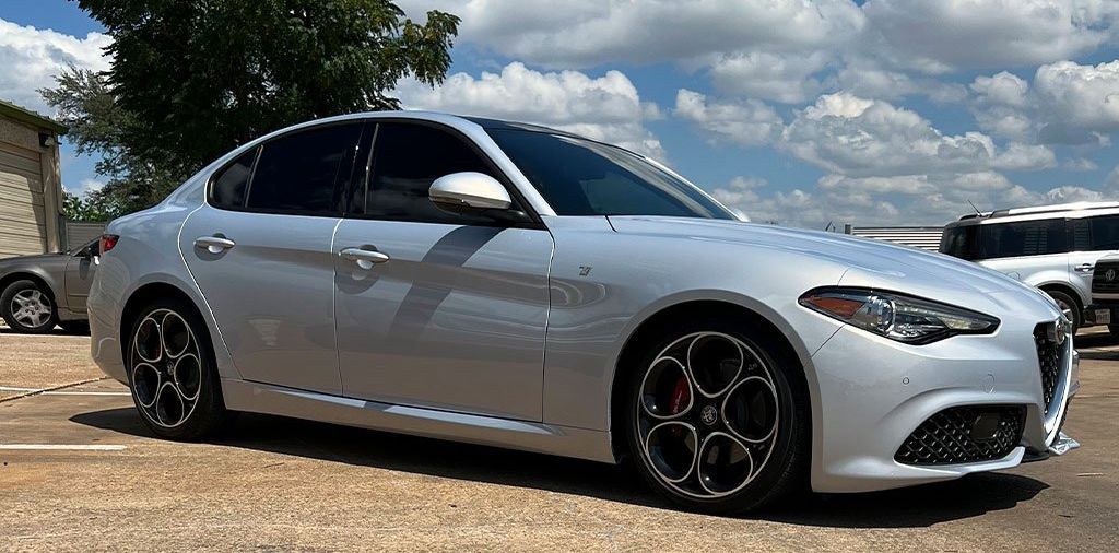 Silver Alfa Romeo Giulia sedan parked outside on a sunny day.