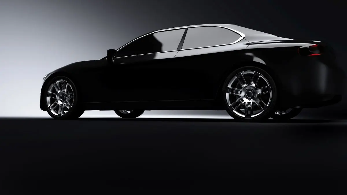 Black sports car on a dark surface, chrome rims, side view.