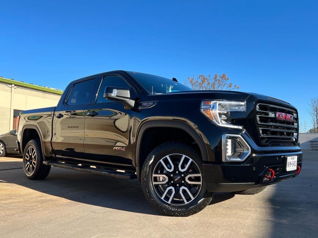 Black GMC Sierra truck on a paved surface, against a clear blue sky.