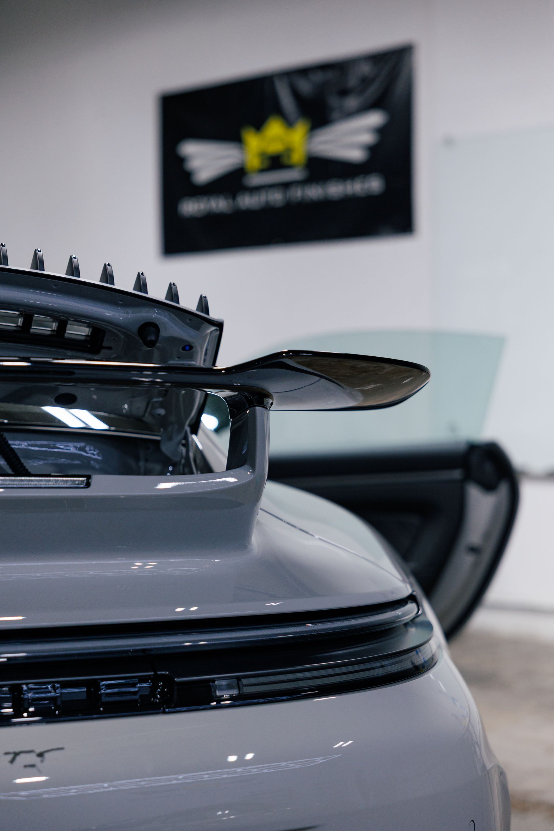 Red Porsche 911 coupe in a garage, black wheels.