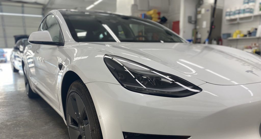 White Tesla car parked in a garage.