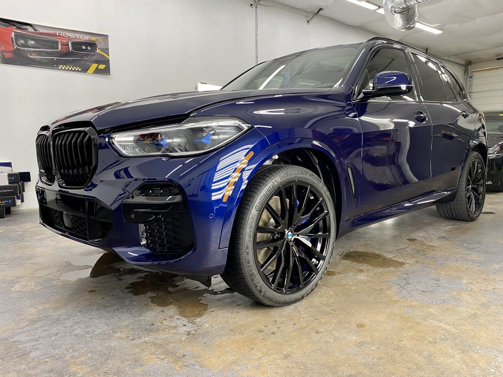 Dark blue BMW SUV with black wheels, parked in a garage.