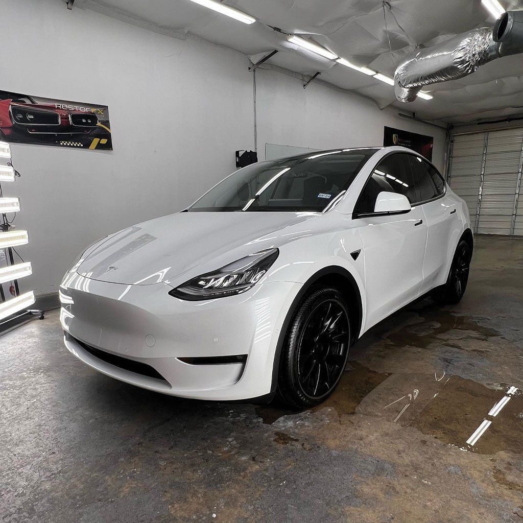 White Tesla Model Y in a garage with black rims.