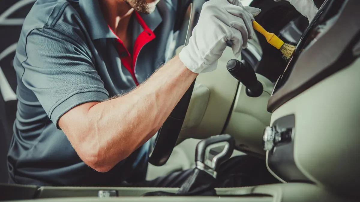 Mechanic in gloves working on a vehicle's dashboard, using tools.