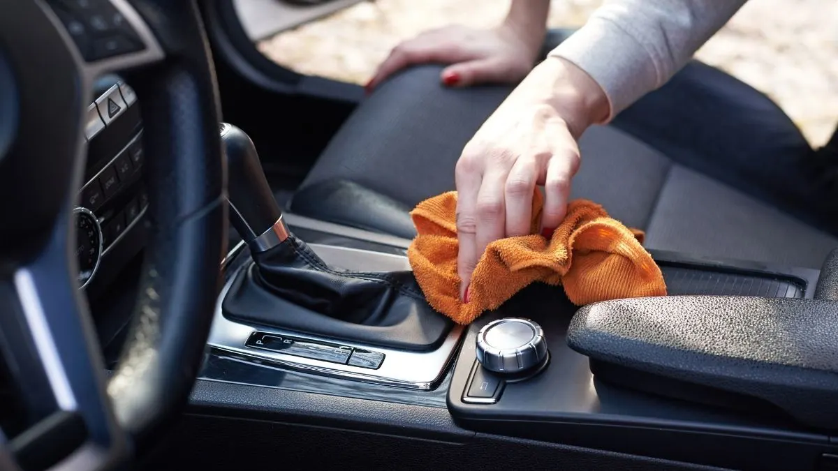 Person cleaning a car's interior with an orange cloth.