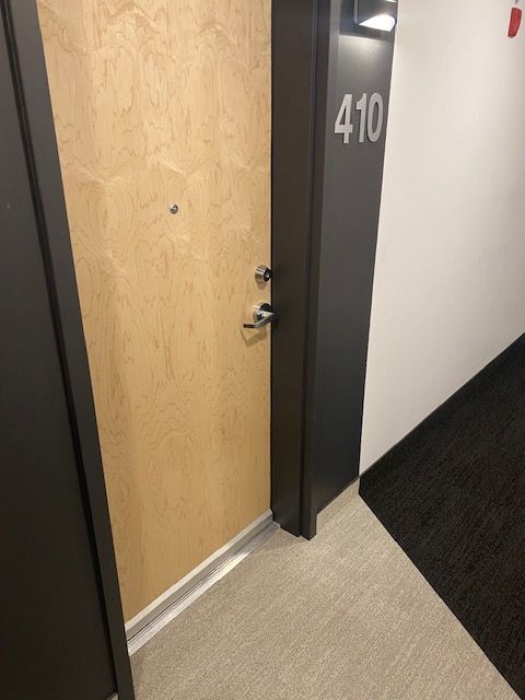 Porte d'appartement numéro 410 sur cadre foncé, dans un couloir avec moquette.