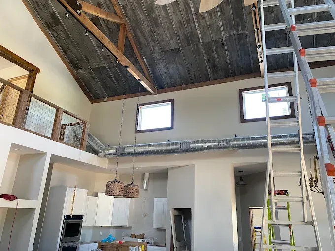 Open-concept room with high exposed wood ceiling, loft railing, windows, and a ladder near the wall