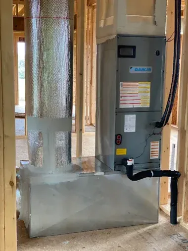 Gray HVAC furnace and ductwork installed beside a window in a utility room